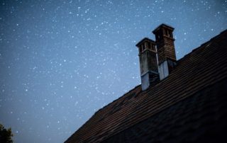 A low shot of chimneys in the roof with the background night sky.