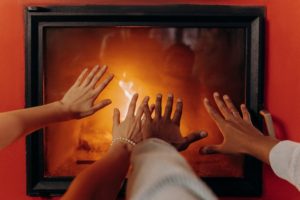 A couple's hands by the fireplace.
