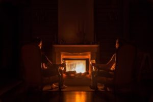 two friends sitting near a fireplace