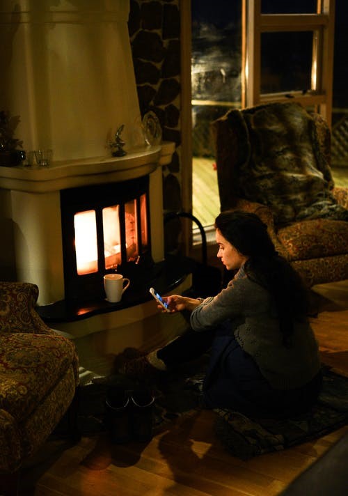 Woman using phone next to fireplace