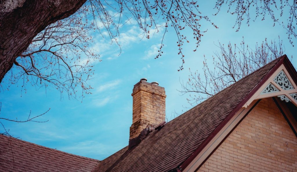 Angular photo of a chimney on a red-bricked roof.