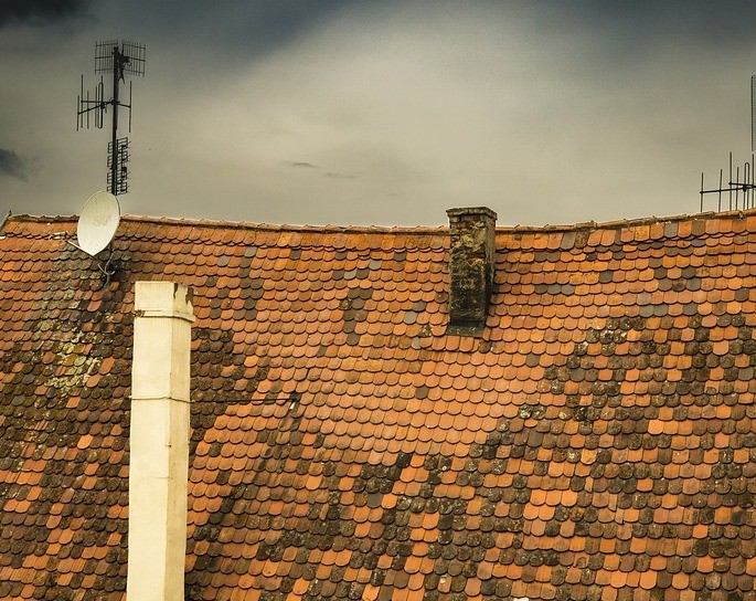 A brown roof house with fractures in the chimney