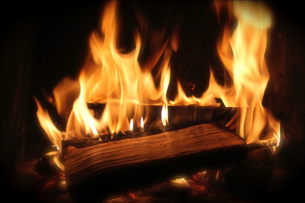 Flames rising from wood burning in a fireplace.